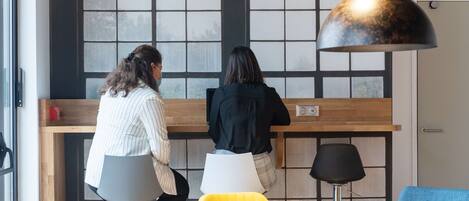 Dos personas sentadas en una mesa con vista a una ventana de diseño cuadriculado.