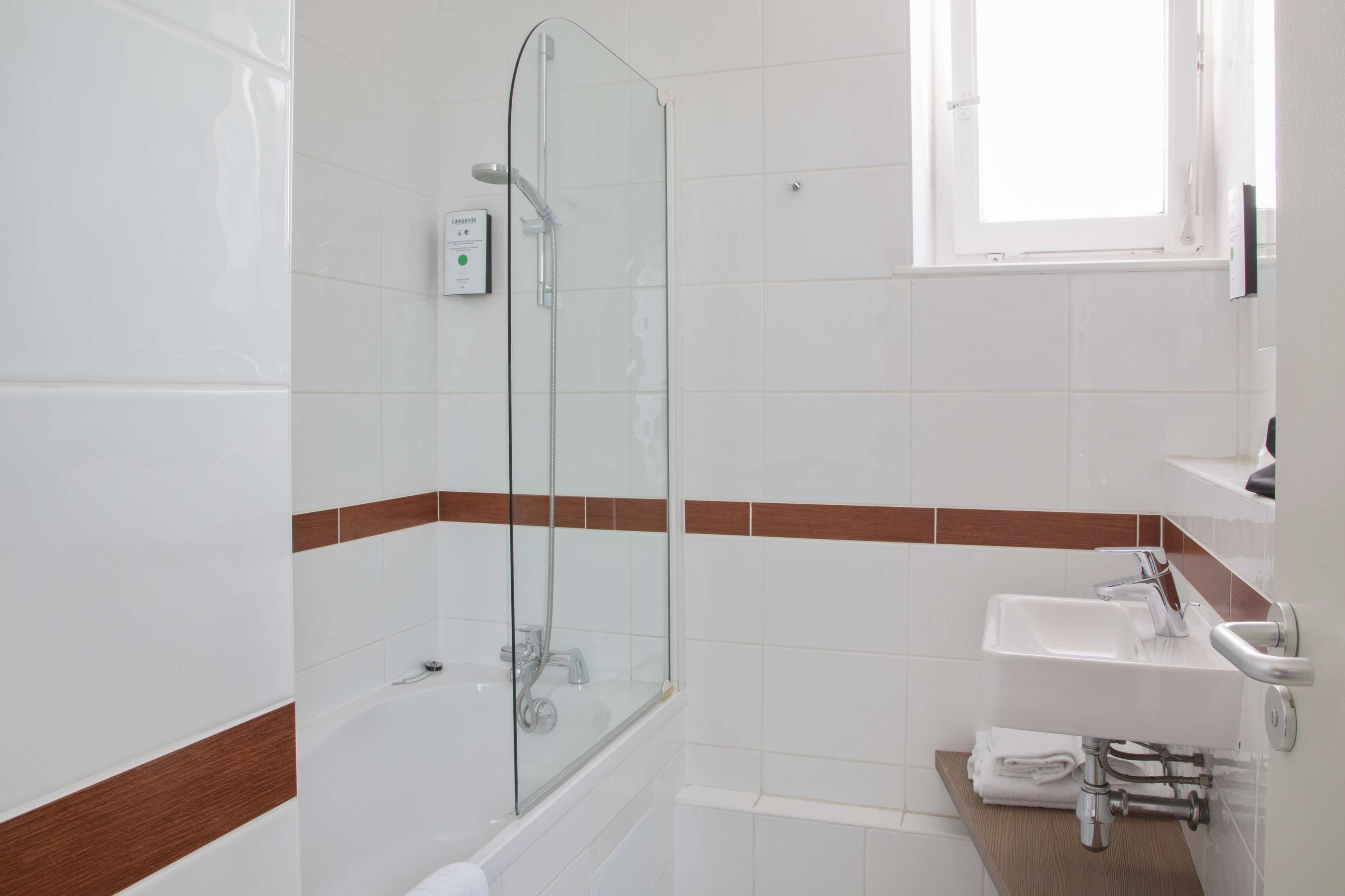 Une salle de bain moderne avec une douche à parois de verre, un lavabo blanc et un porte-serviettes.