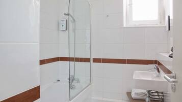 Une salle de bain moderne avec une douche à parois de verre, un lavabo blanc et un porte-serviettes.