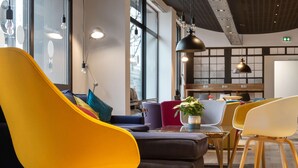 A modern interior with yellow and white chairs, a black sofa, and a wooden table. - Campanile Epinal Centre - Gare (Epinal)