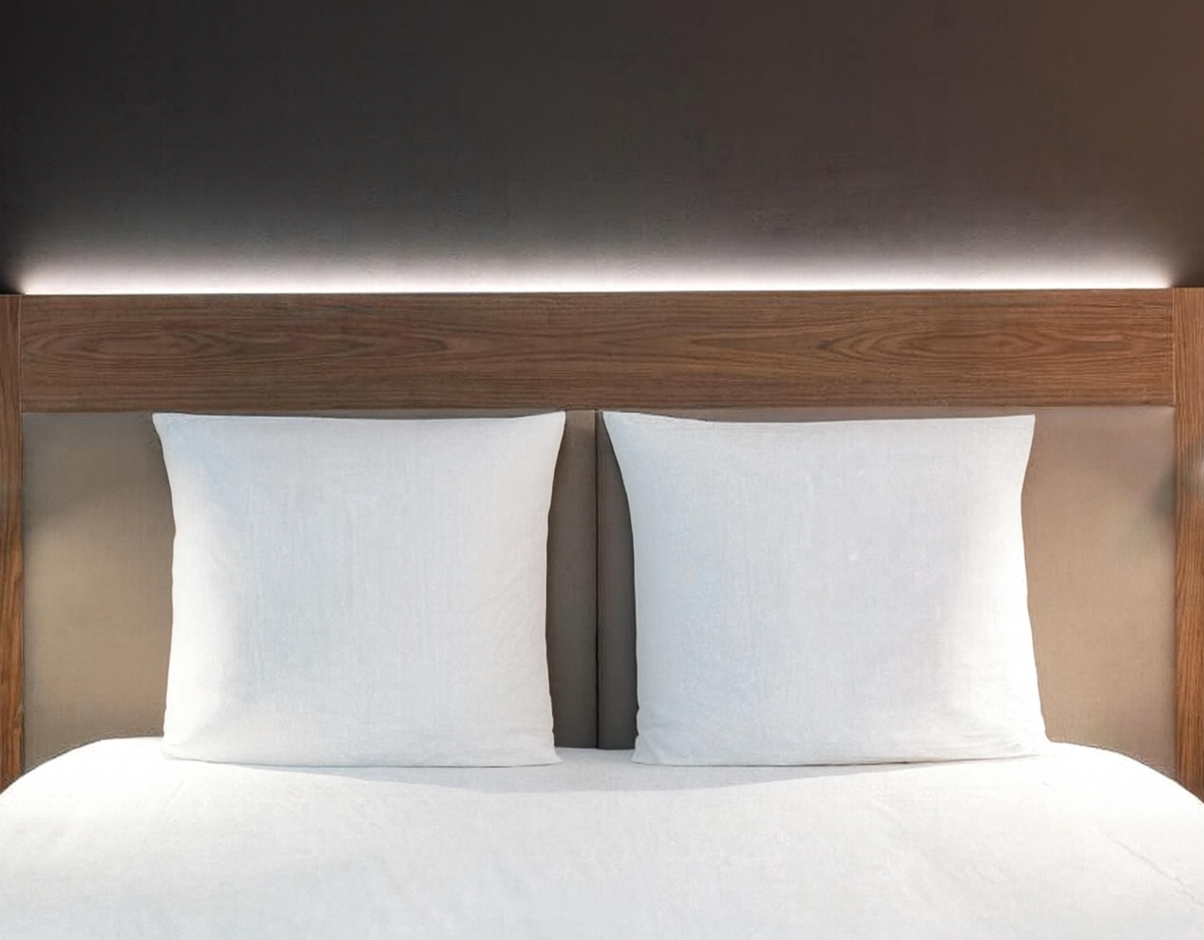 Uma cama com cabeceira de madeira e duas almofadas.