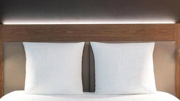 Uma cama com cabeceira de madeira e duas almofadas.