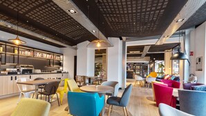 A modern interior with a kitchen area, dining space, and seating with colorful chairs. - Campanile Epinal Centre - Gare (Epinal)