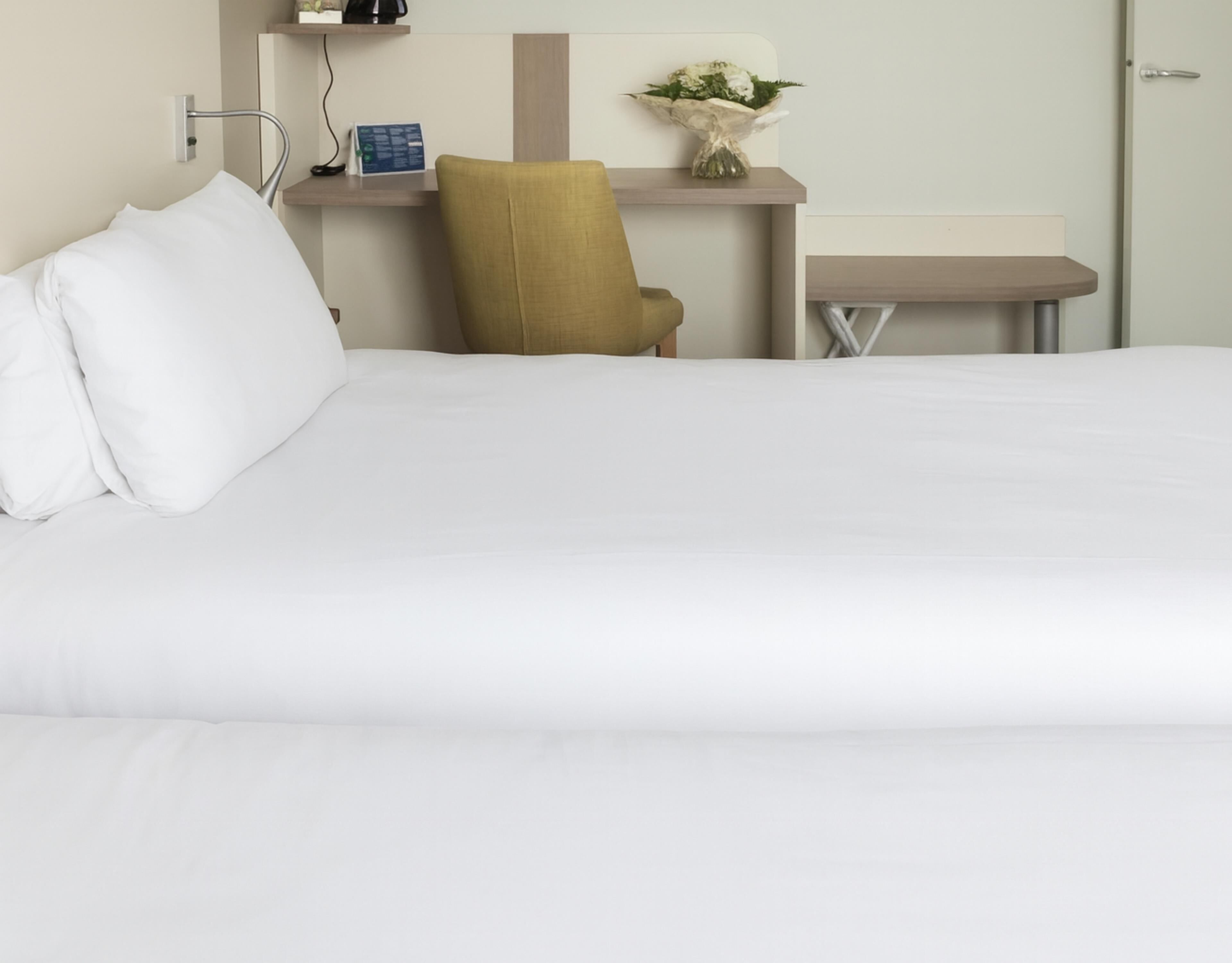 Een hotelkamer met een bed, een bureau, een stoel en een kleine tafel.