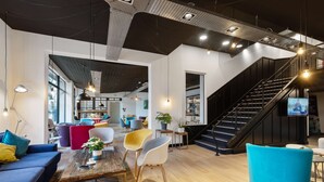 A modern interior with a staircase, seating areas, and a television. - Campanile Epinal Centre - Gare (Epinal)