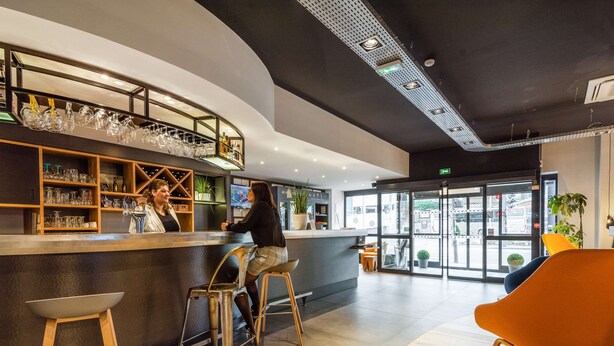 A modern bar area with stools, a counter, and shelves with glassware. - Campanile Epinal Centre - Gare (Epinal)