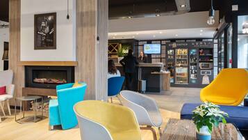 A modern hotel lobby with a fireplace, seating area, and a reception desk.