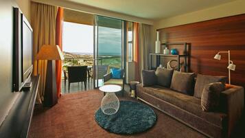 Habitación de hotel con sofá, una mesita, una lámpara y vistas al exterior.