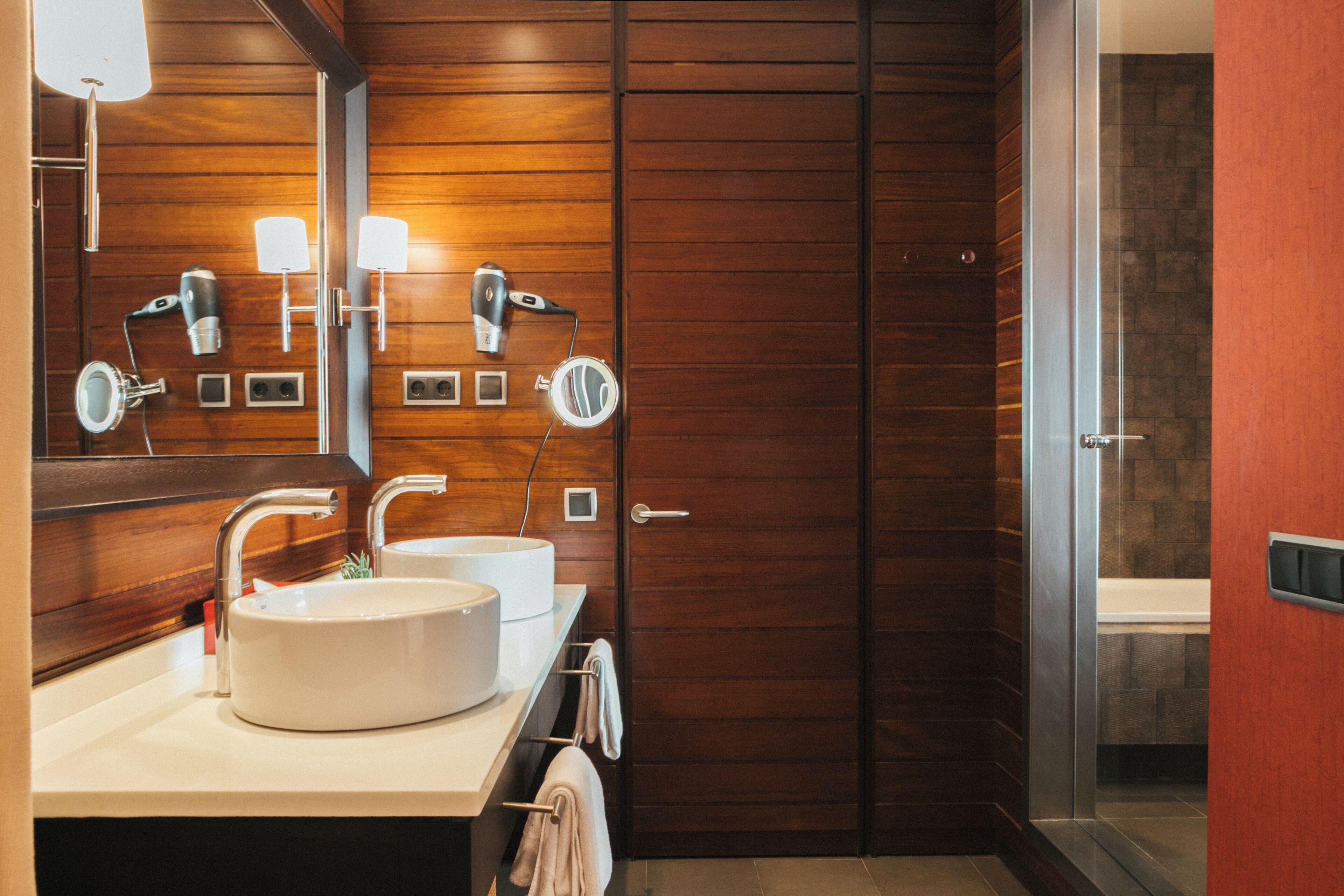 Un baño moderno con dos lavamanos, un espejo grande y un secador de pelo.