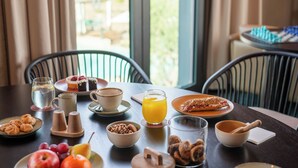 A breakfast table with various food items, a glass of orange juice, and a chessboard in the background. - Salobre Hotel Resort & Serenity (San Bartolomé de Tirajana)
