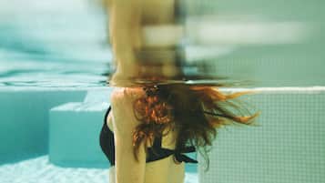 Una persona sumergida en el agua, con un fondo de azulejos.