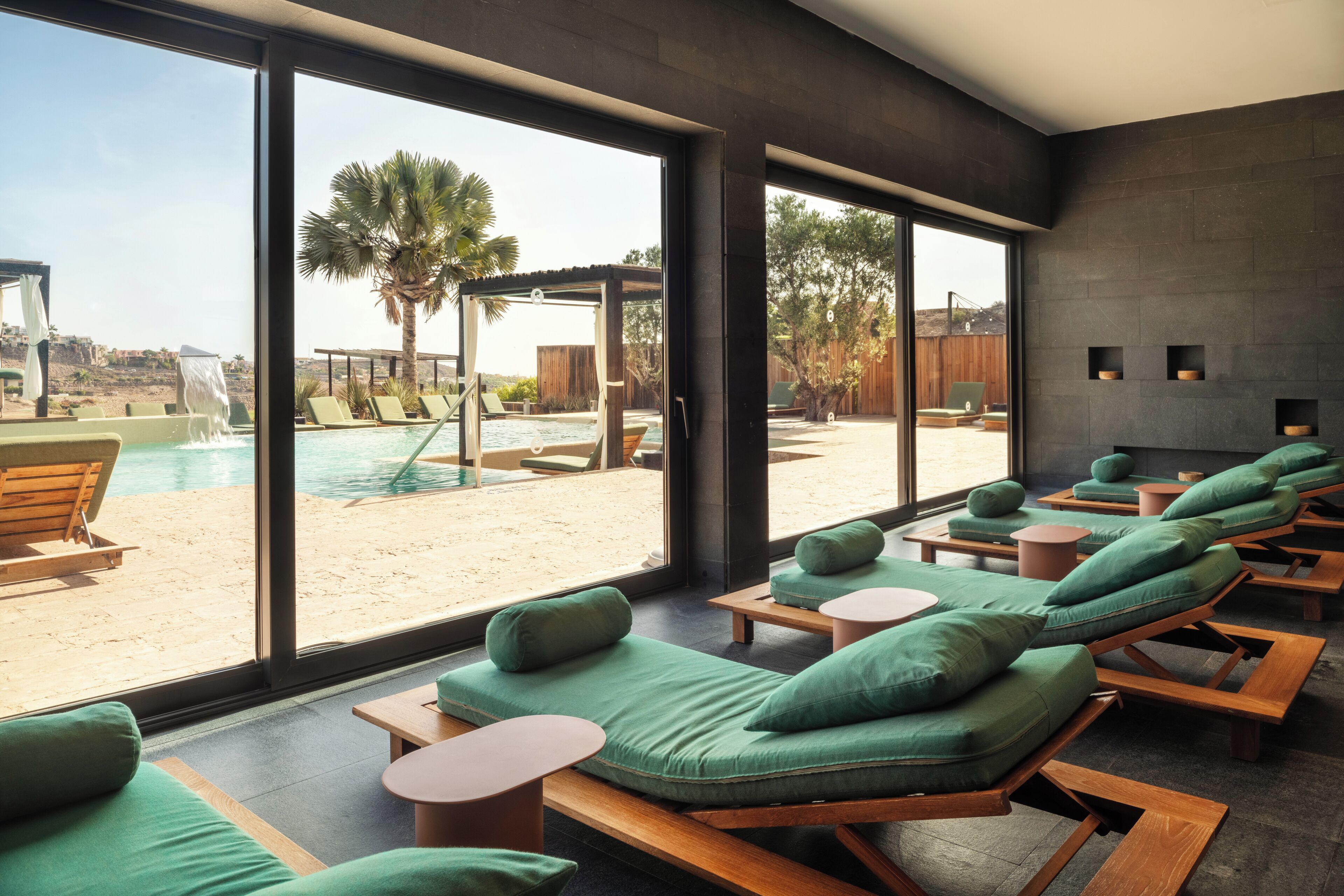 A modern spa area with sun loungers, a pool, and a view of the beach.