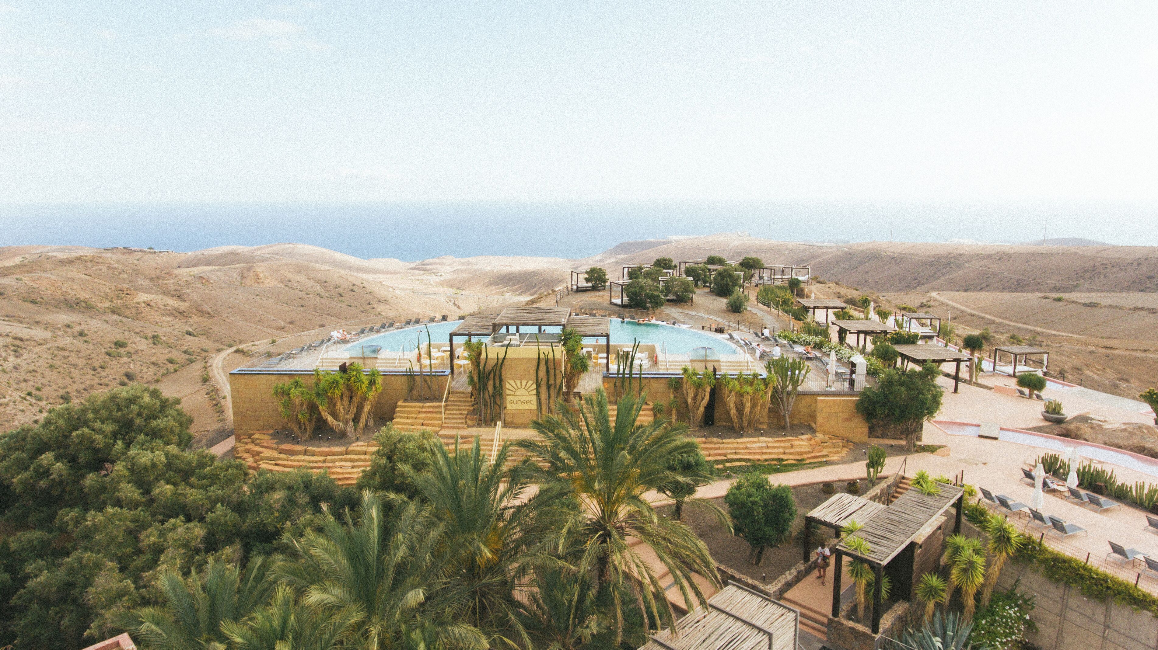 A resort with a large pool, palm trees, and a desert landscape.