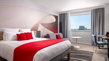 Une chambre d’hôtel moderne avec un grand lit, une petite table et une vue sur la ville.