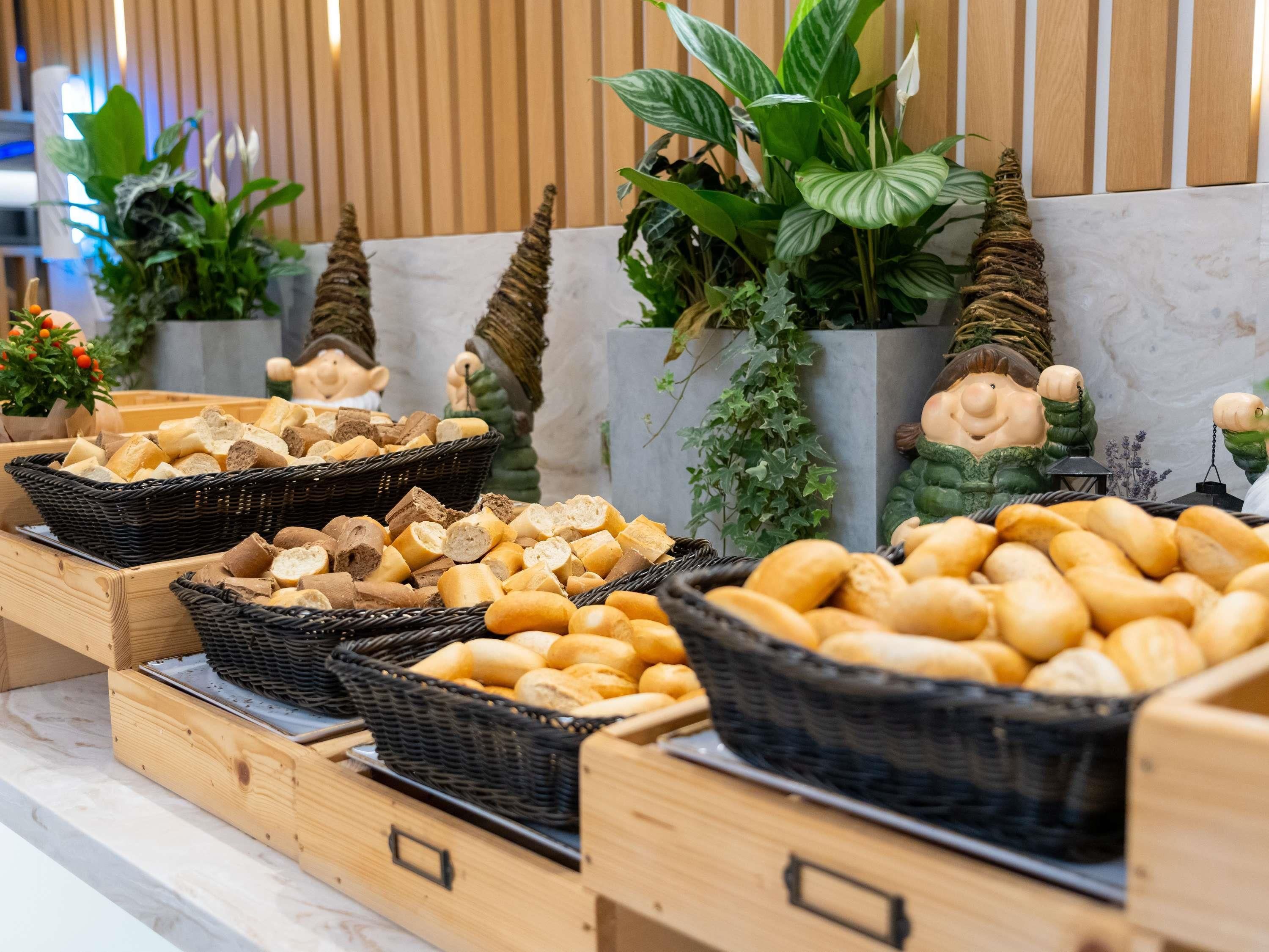 A buffet with various types of bread displayed in baskets.
