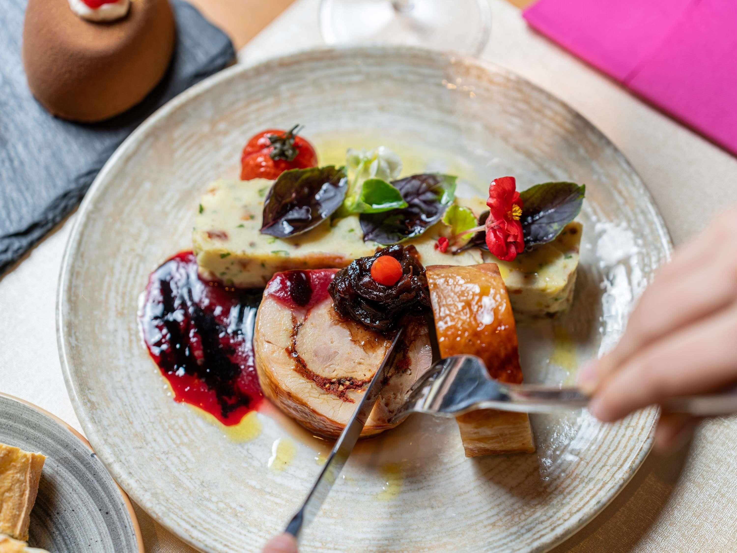 A plate of food with a variety of items including a piece of meat, a pastry, and some vegetables.