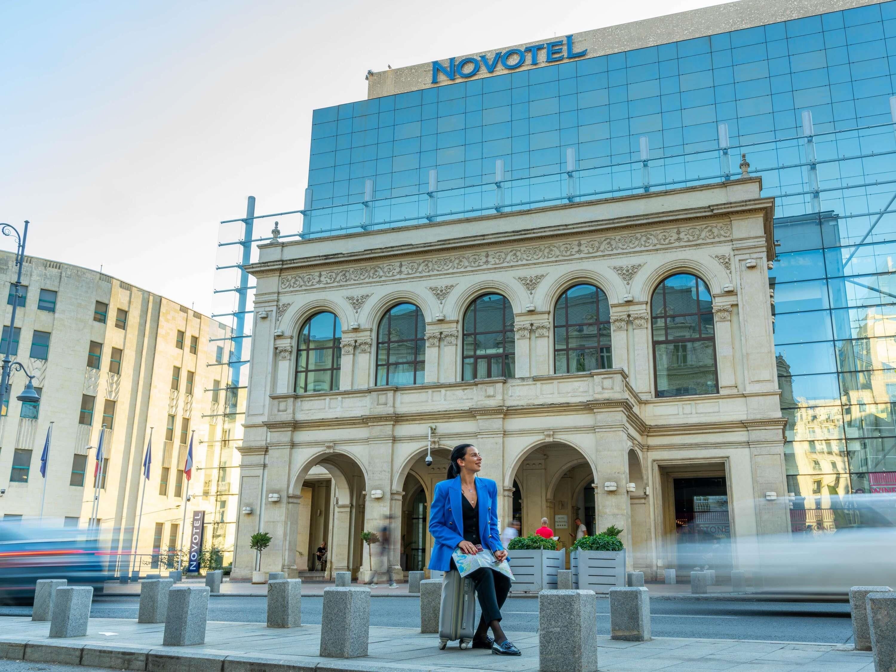 Un hotel con una facciata classica e un edificio moderno in vetro.