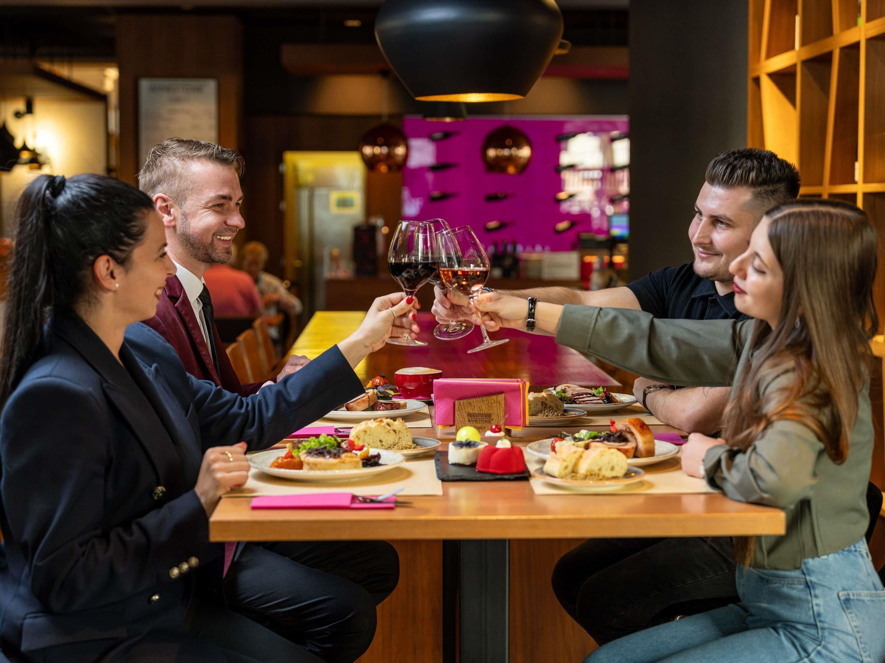 Un grupo de personas brindando con copas de vino en una mesa de restaurante con varios platos.