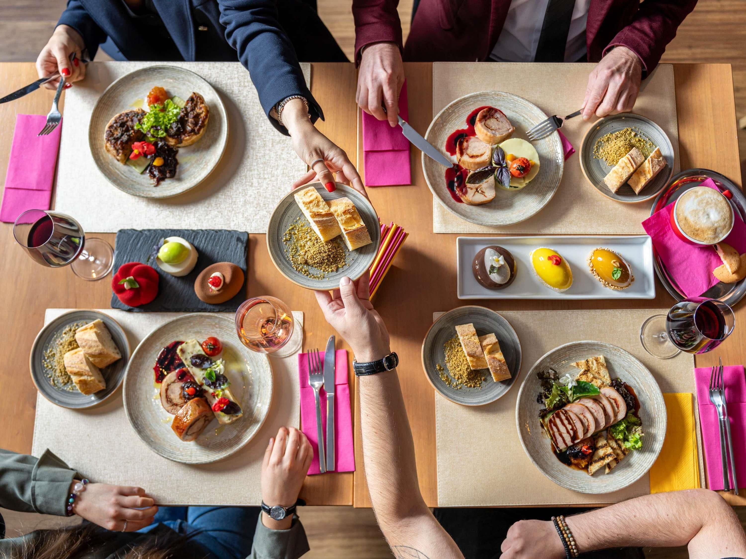 Un groupe de personnes est réuni autour d’une table, où se trouvent divers plats et boissons.
