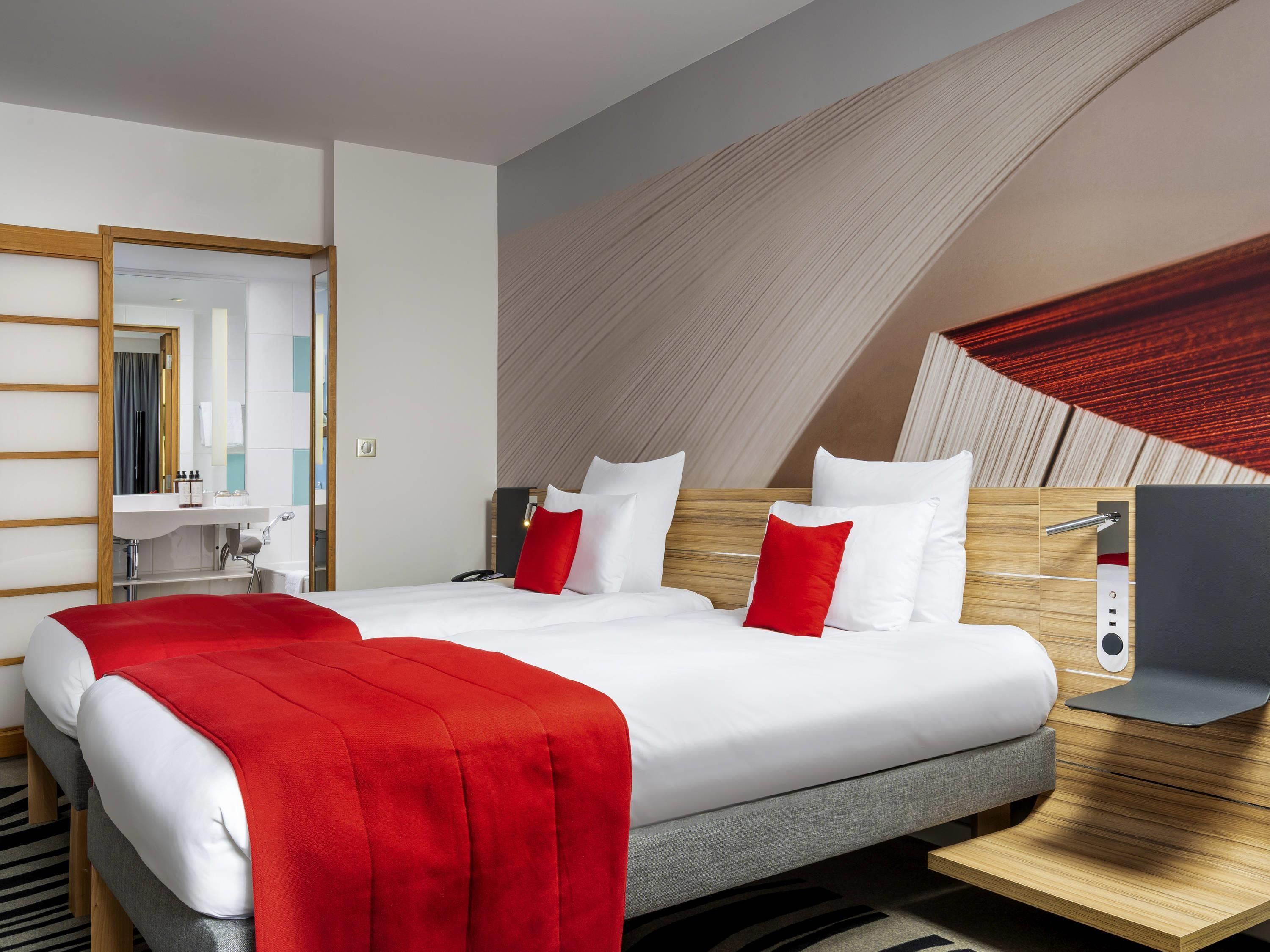 Una habitación de hotel moderna con una cama grande, un escritorio y un espejo.