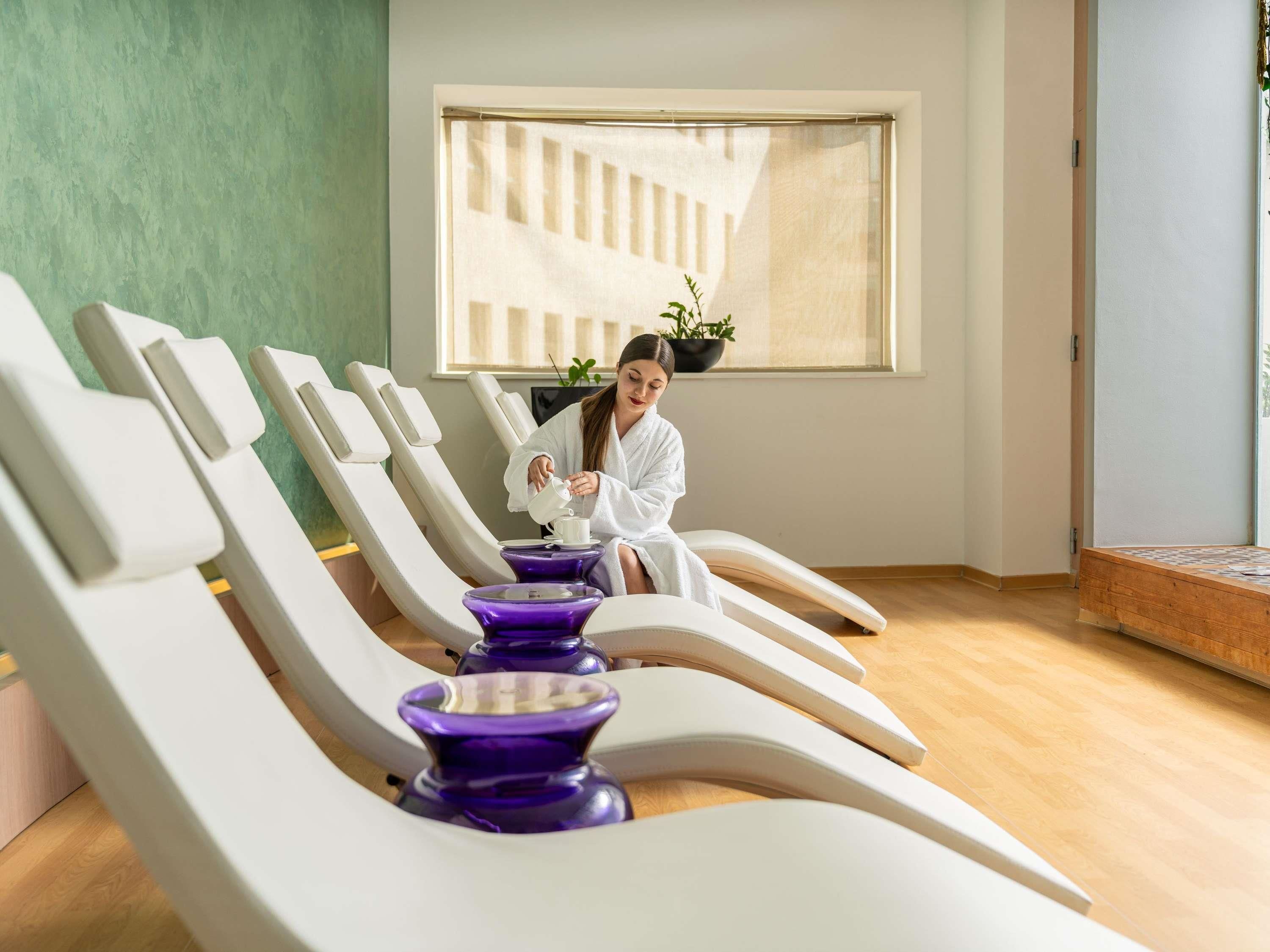 A spa room with reclining chairs, a window with a view, and a plant on the windowsill.
