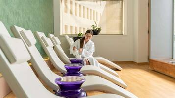 A spa room with reclining chairs, a window with a view, and a plant on the windowsill.