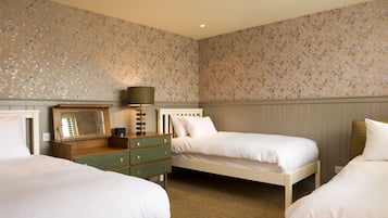 A bedroom with two single beds, a wooden dresser with drawers, a mirror, and a lamp.