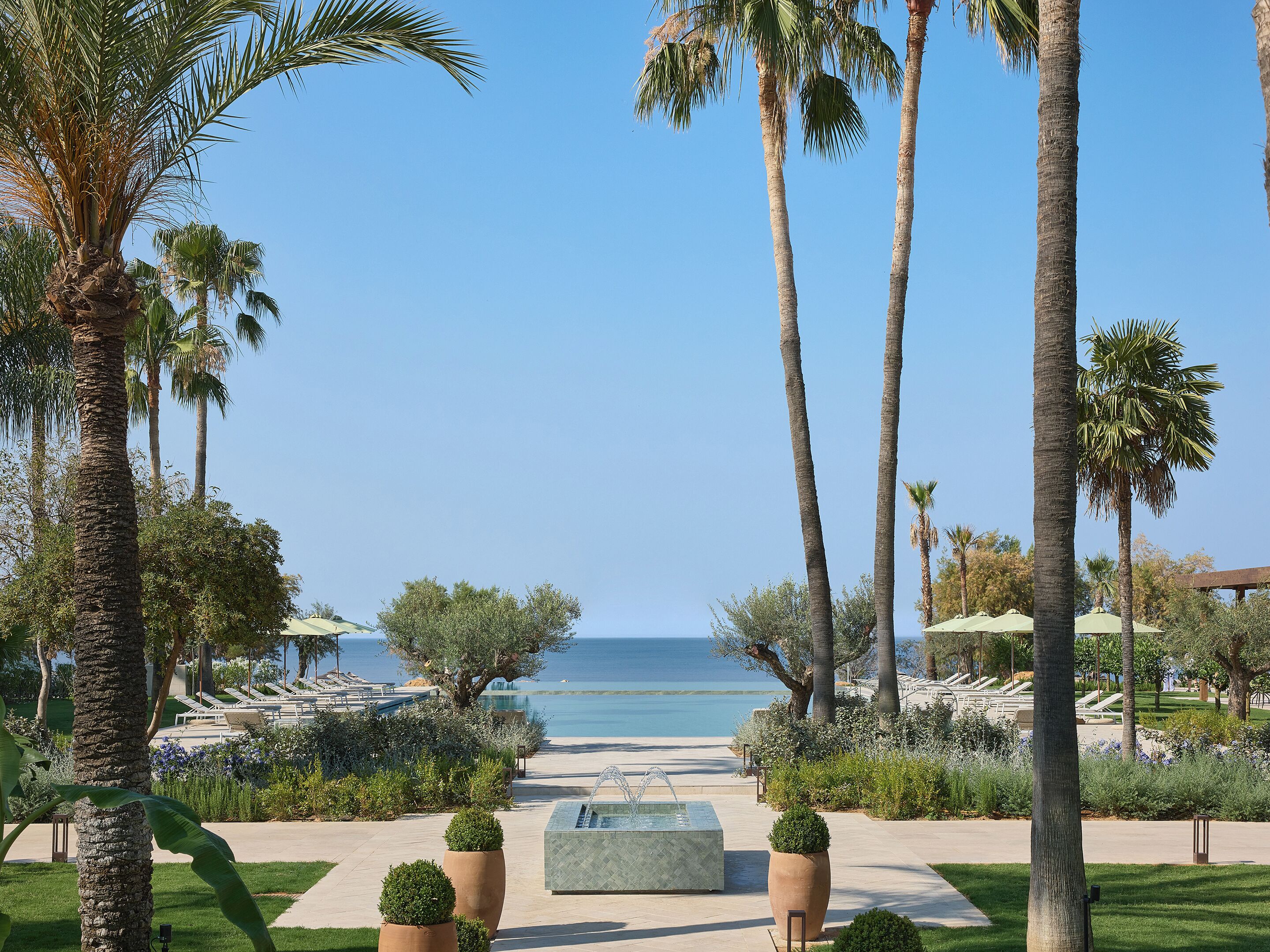 A resort with palm trees, a pool area, and a view of the ocean.