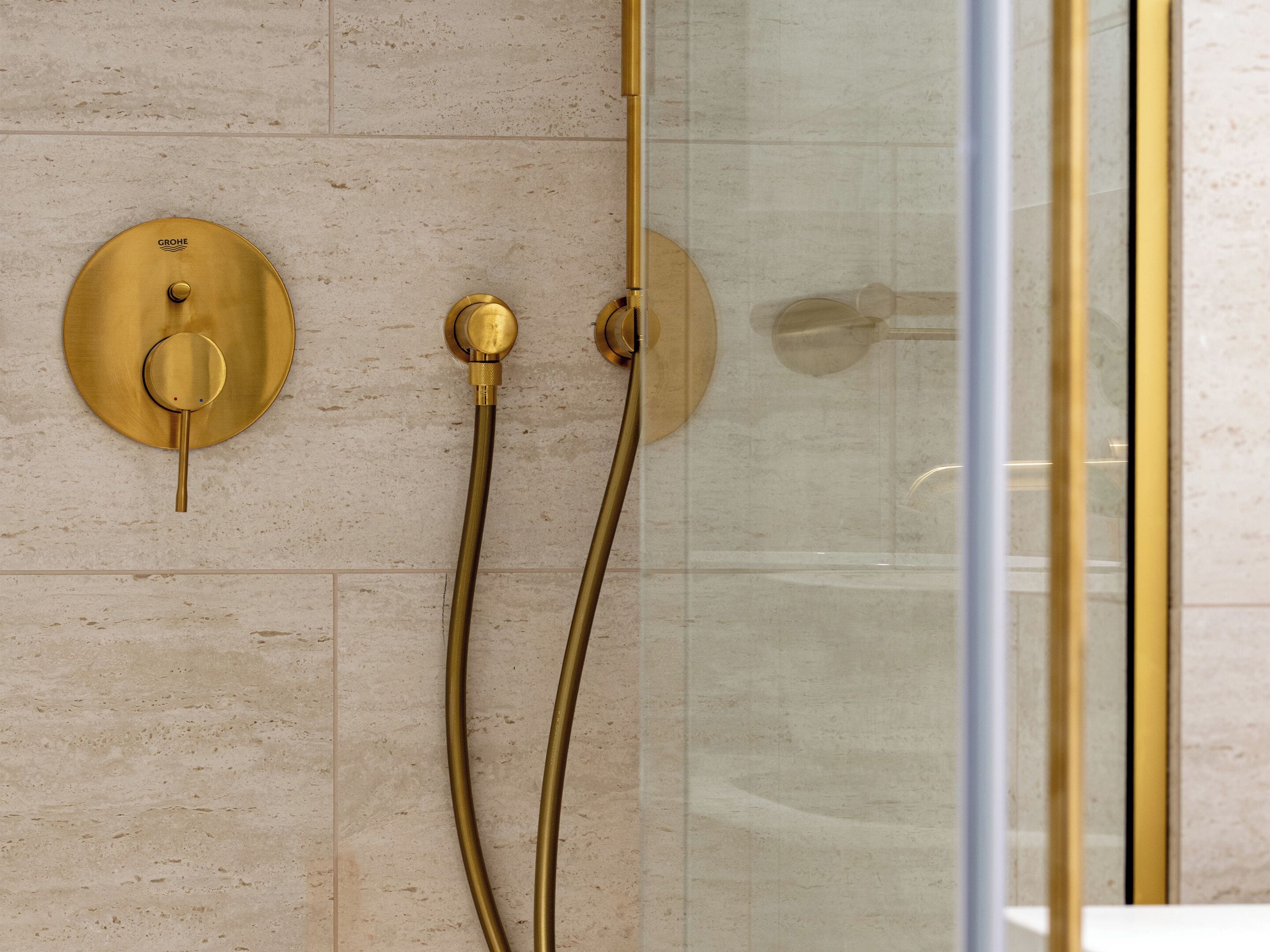 A shower with gold fixtures and a glass enclosure.