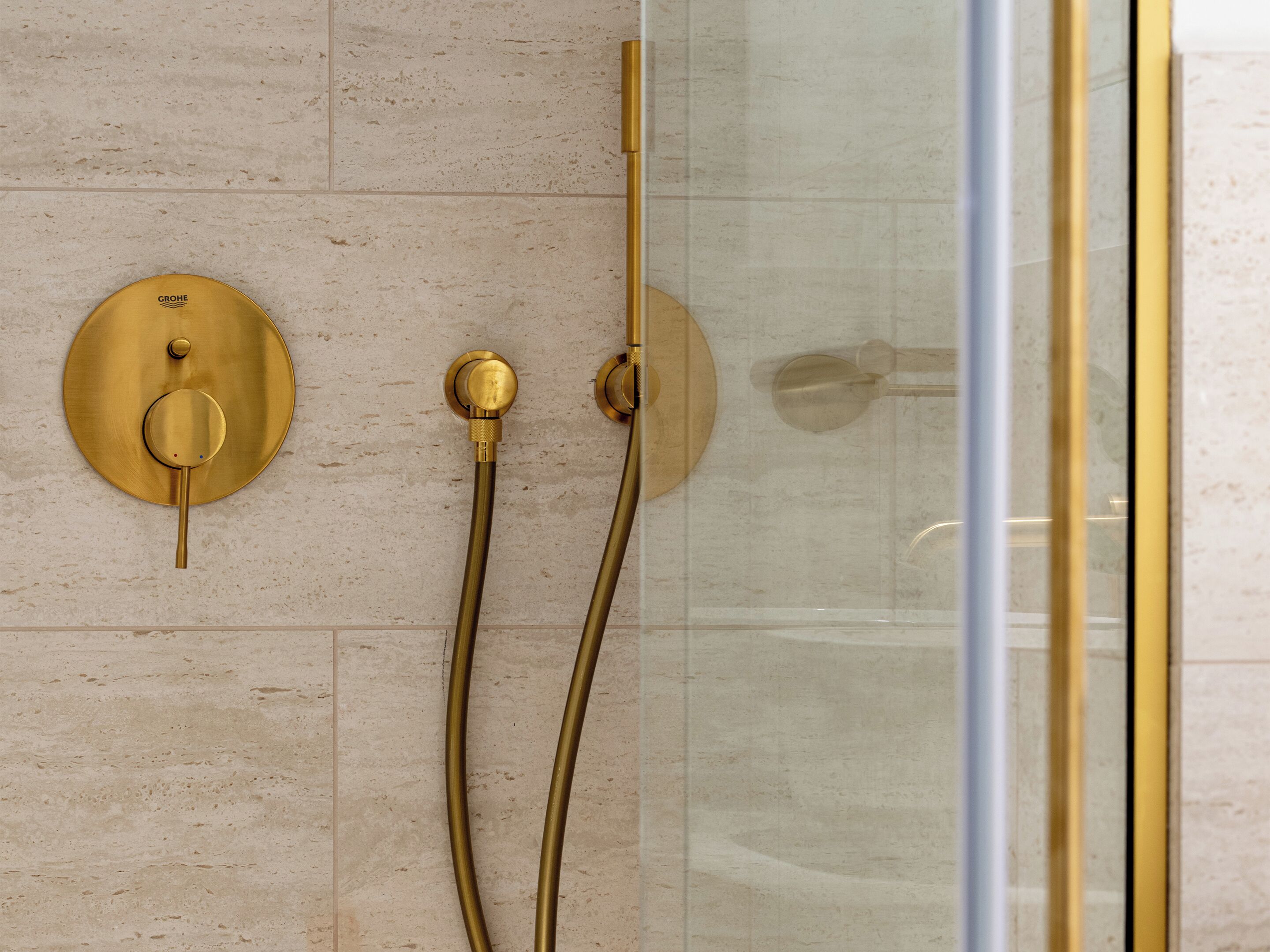 A shower with gold fixtures and a glass door.