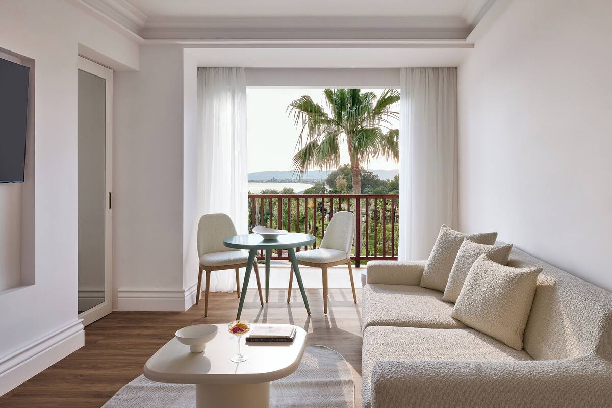 Un salon moderne avec un balcon, un canapé, une table et un téléviseur.