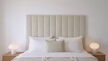 A bedroom with a large bed, two bedside tables with lamps, and a textured headboard.