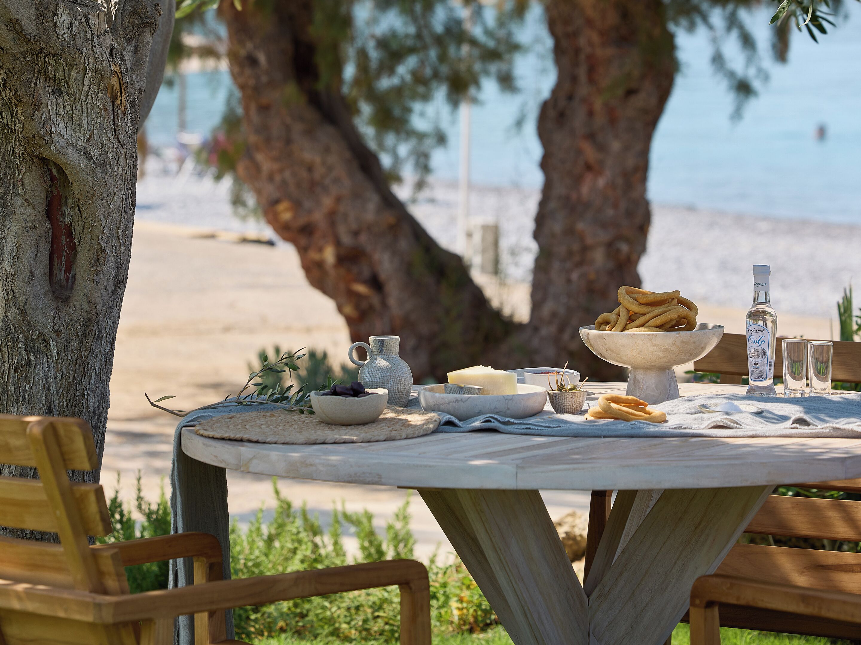Une table ronde installée à l’extérieur, offrant une vue sur une plage et des arbres en arrière-plan.
