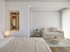 A modern bedroom with a bed, a sofa, a coffee table, a mirror, and a walk-in closet.