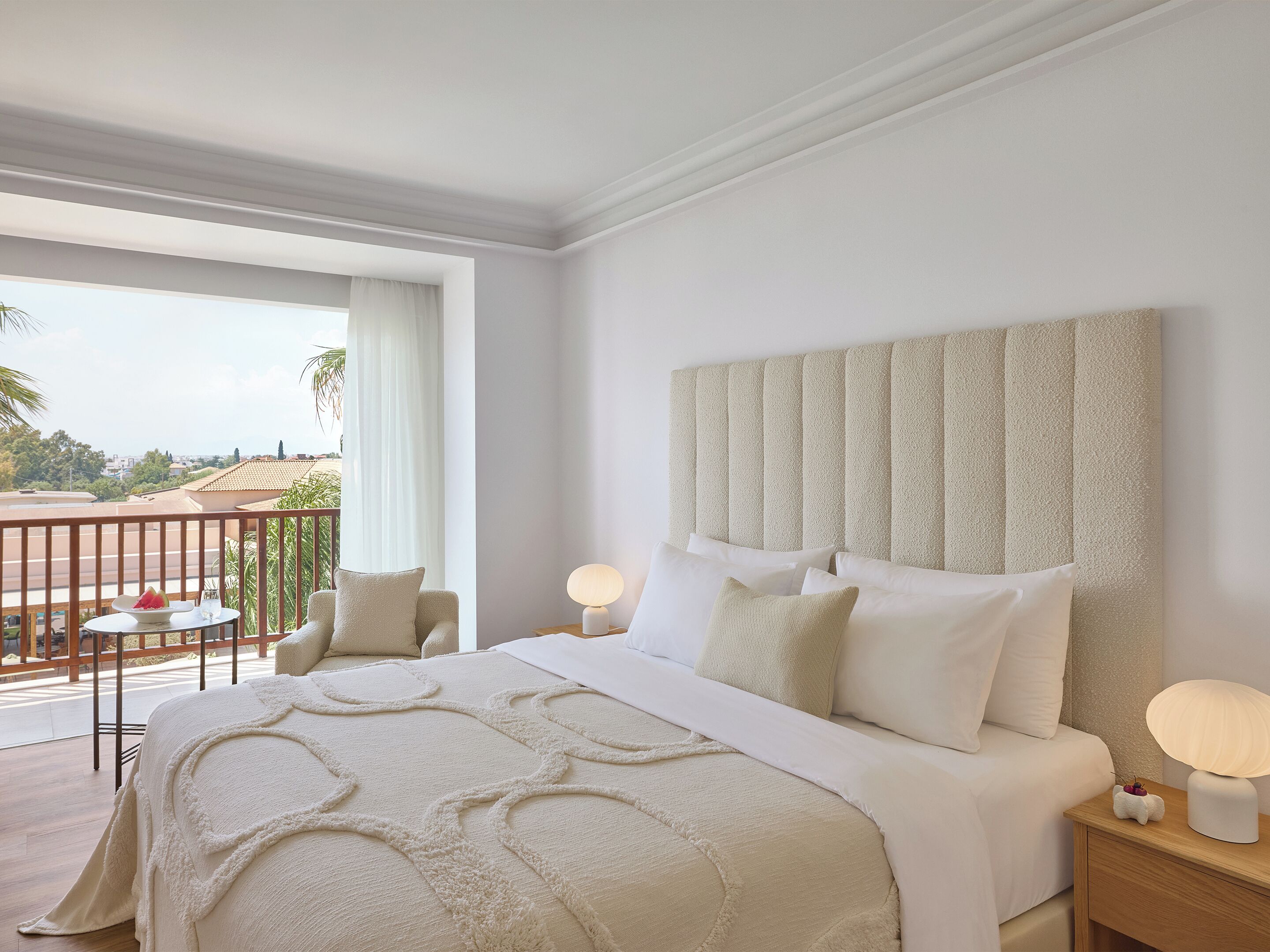 Una habitación de hotel con una cama grande, un balcón con vistas y un cabecero moderno.