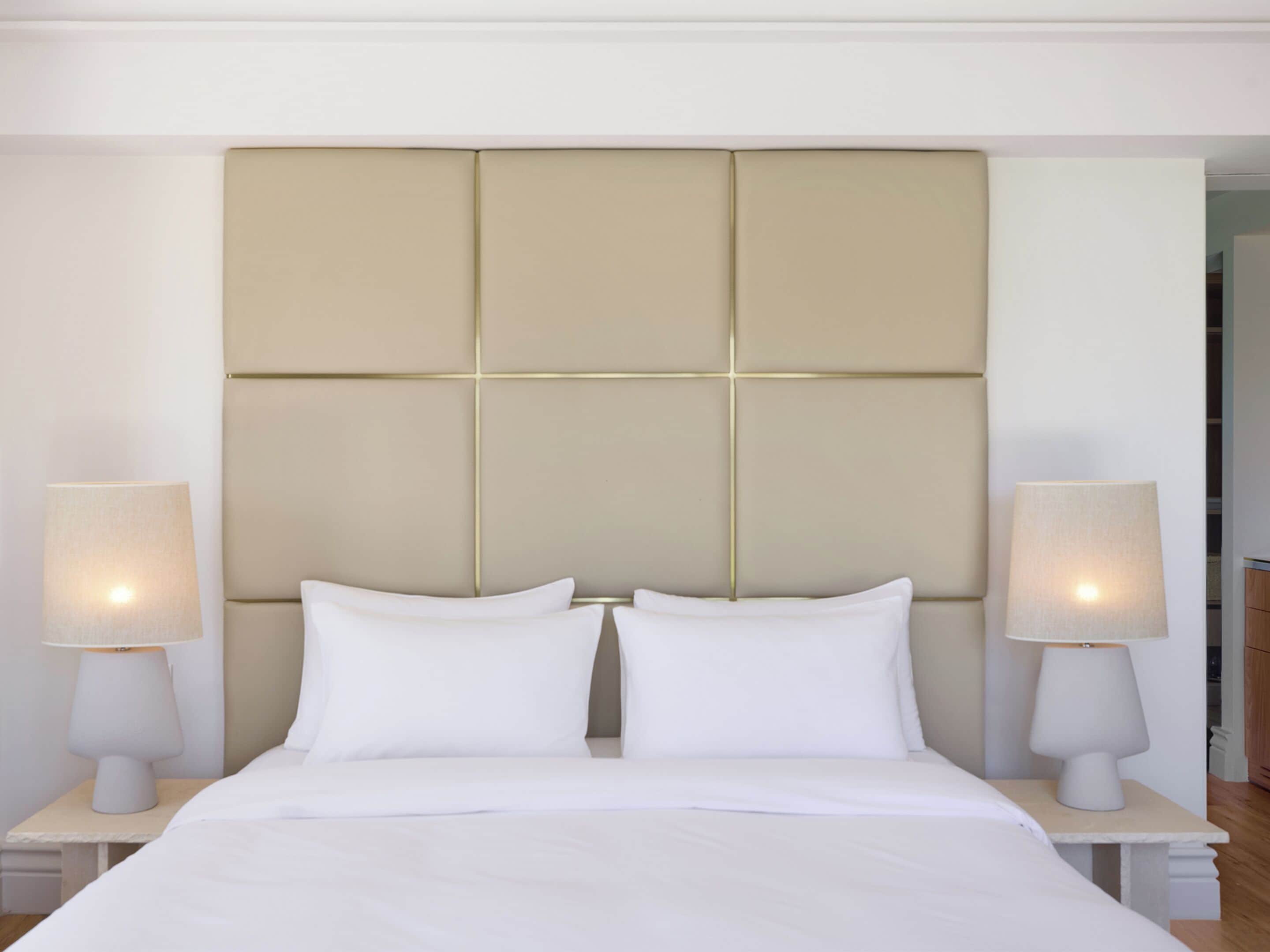 A hotel room with a large bed, two bedside tables with lamps, and a padded headboard.