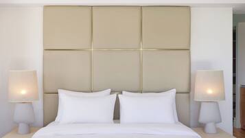 A hotel room with a large bed, two bedside tables with lamps, and a padded headboard.