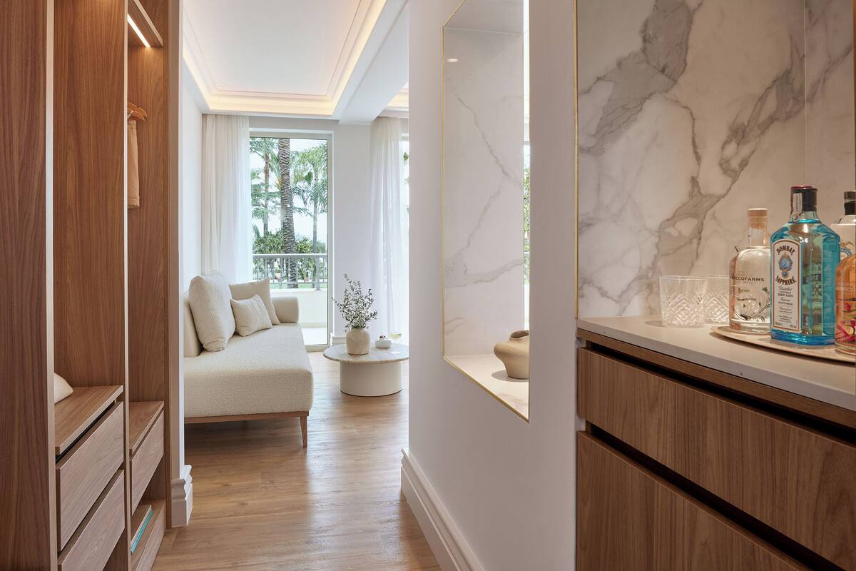 Une salle de bain moderne avec un meuble-lavabo en marbre, un canapé et une vue sur des palmiers.
