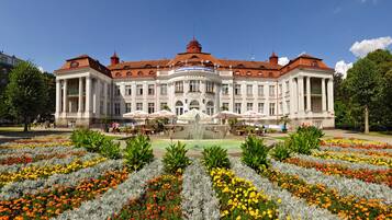 Ein großes, historisches Gebäude mit einer zentralen Fontäne und einer symmetrischen Fassade.