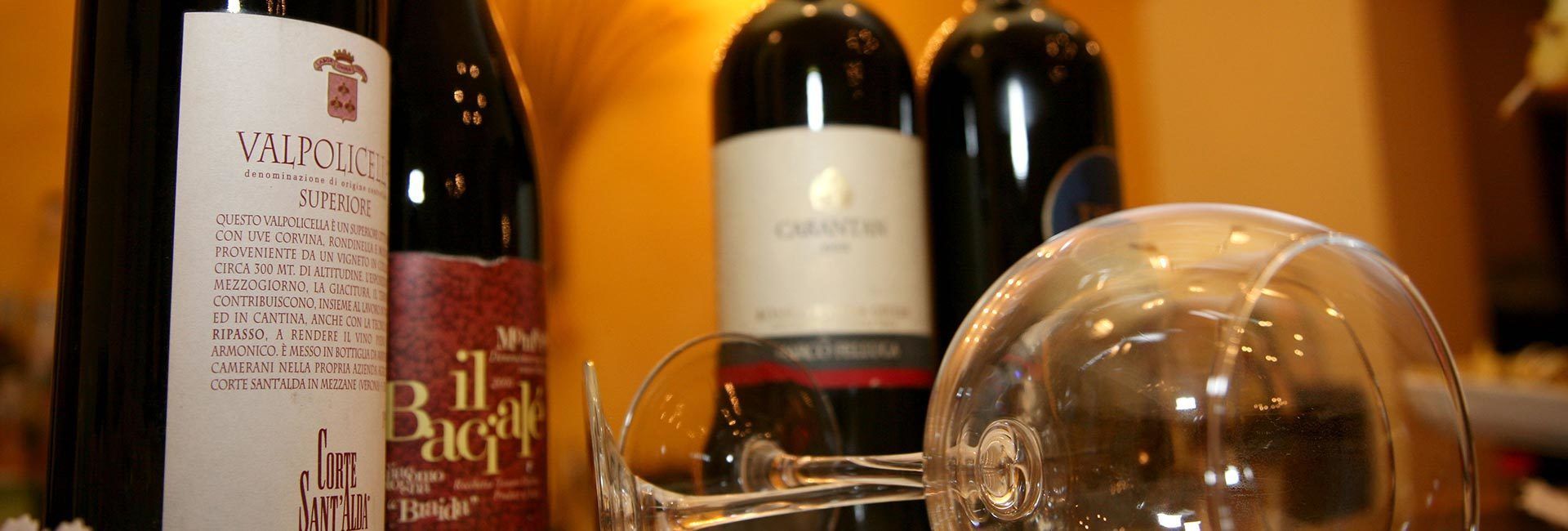 Une bouteille de vin avec une étiquette, un verre à vin et d’autres bouteilles en arrière-plan.