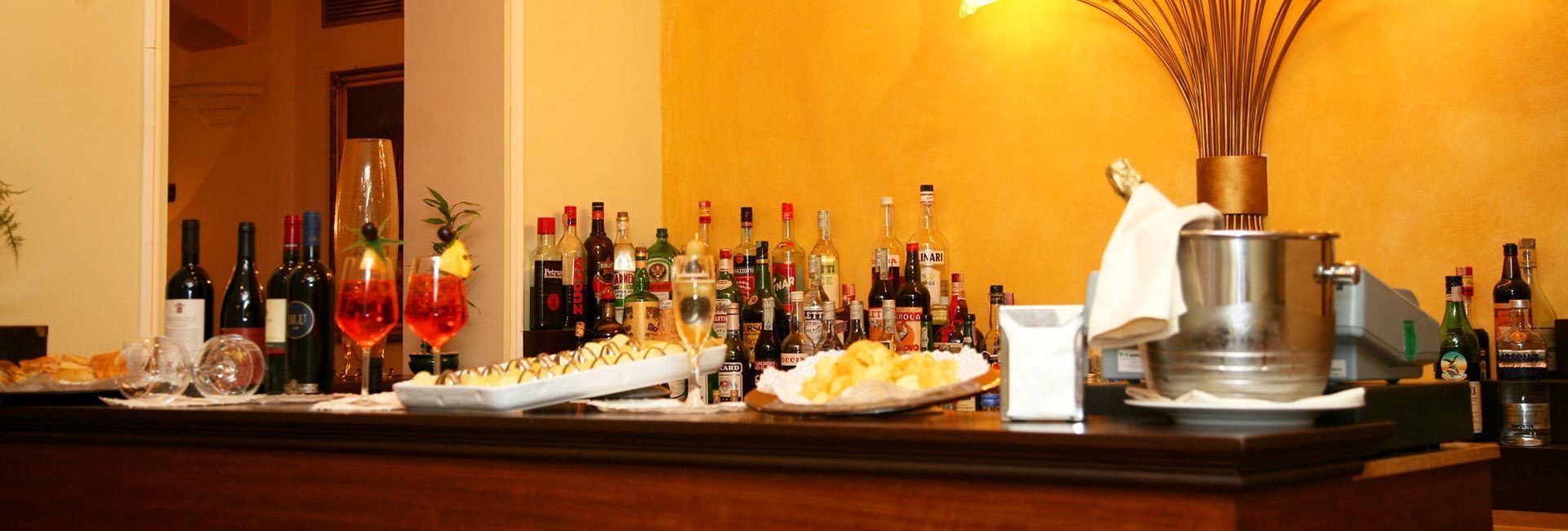 Eine Bar mit verschiedenen Spirituosenflaschen, Gläsern und einer Platte mit Speisen.