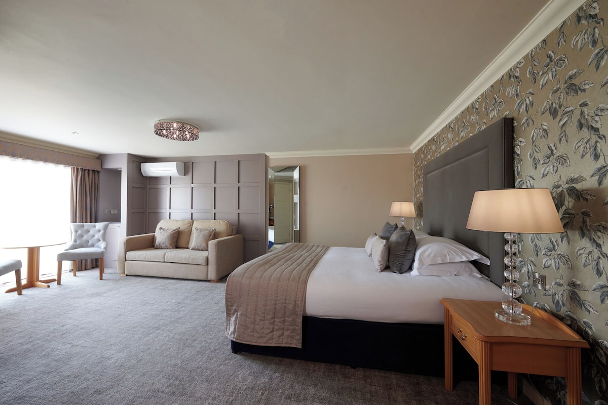 Een hotelkamer met een bed, een bank, een tafeltje en een lamp.
