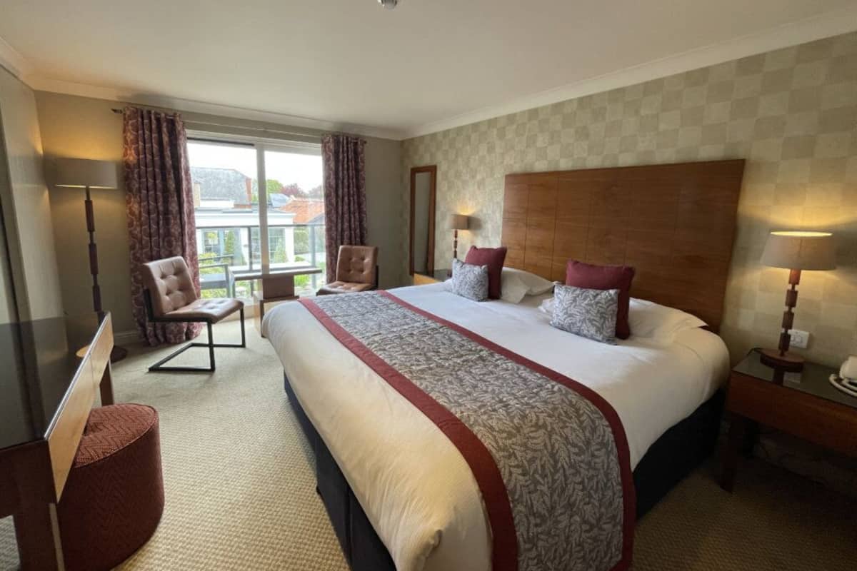 Een hotelkamer met een groot bed, een bureau, een stoel en uitzicht op de stad.
