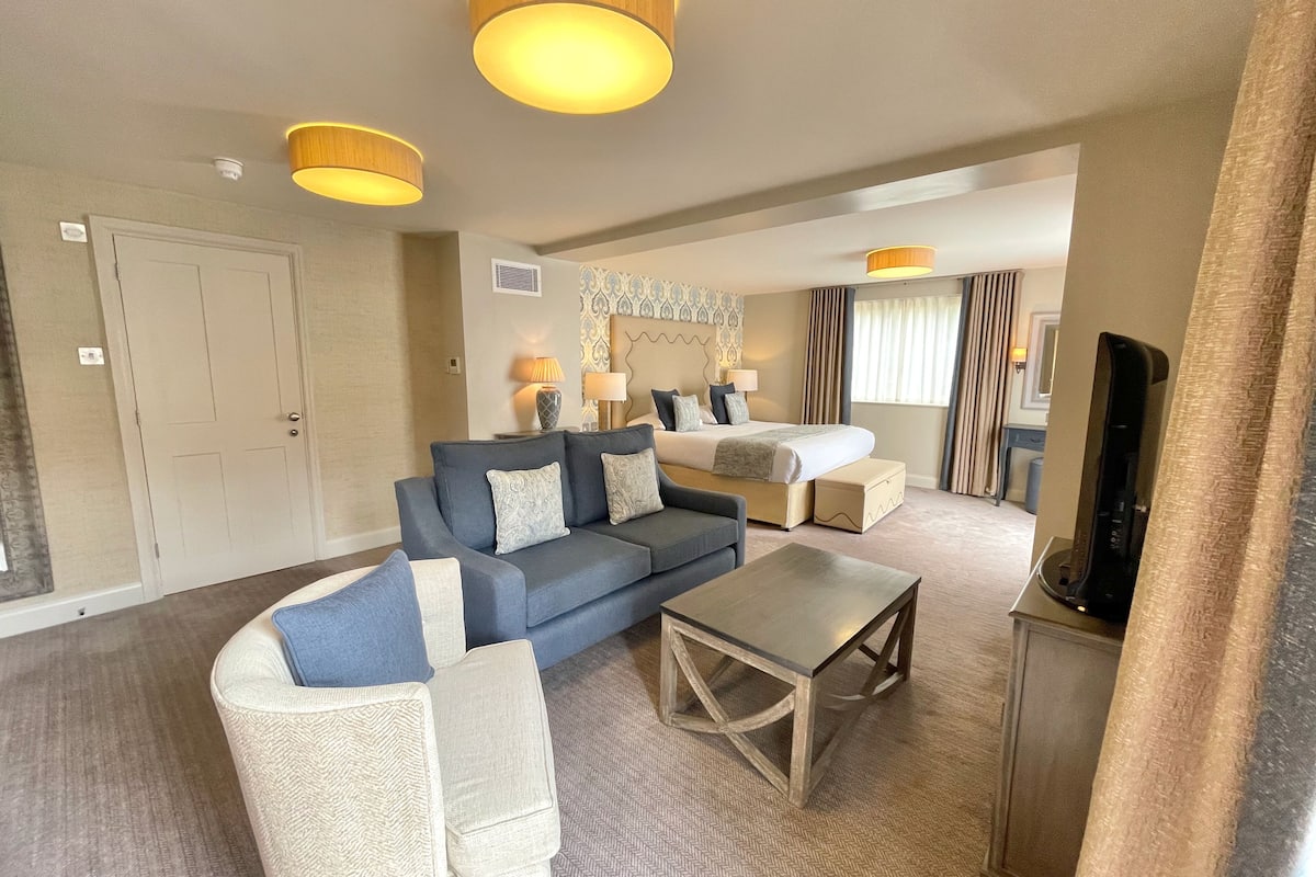 Een hotelkamer met een groot bed, een bank, een salontafel en een televisie.