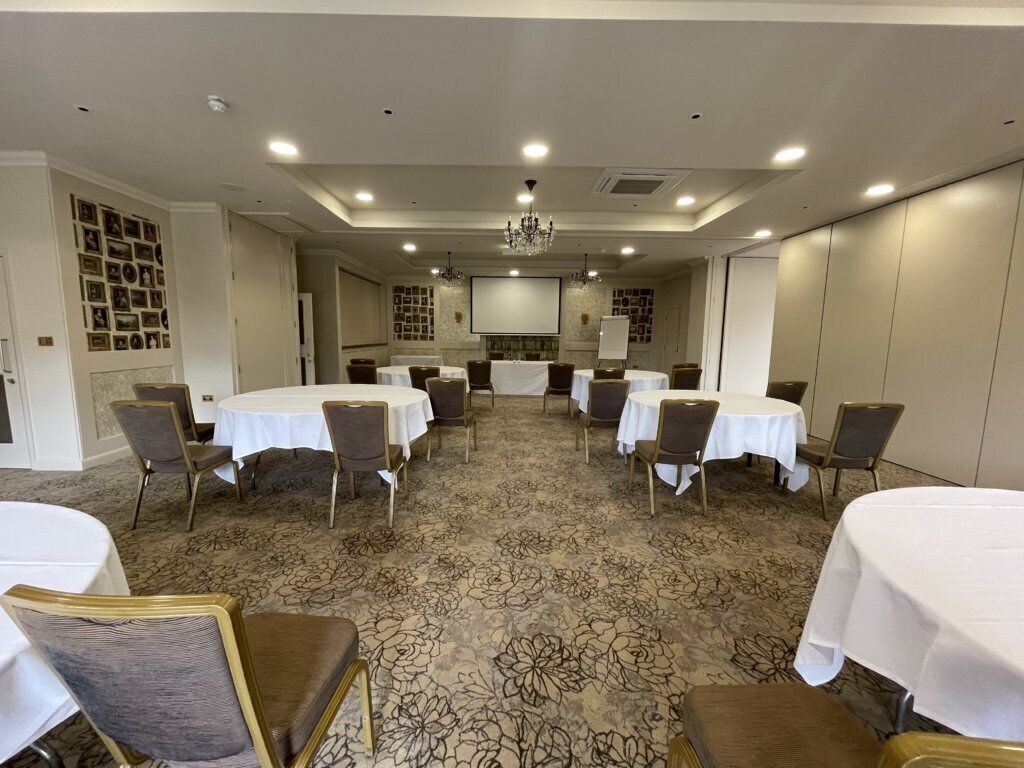 A conference room with round tables and chairs, a carpeted floor, and a chandelier.