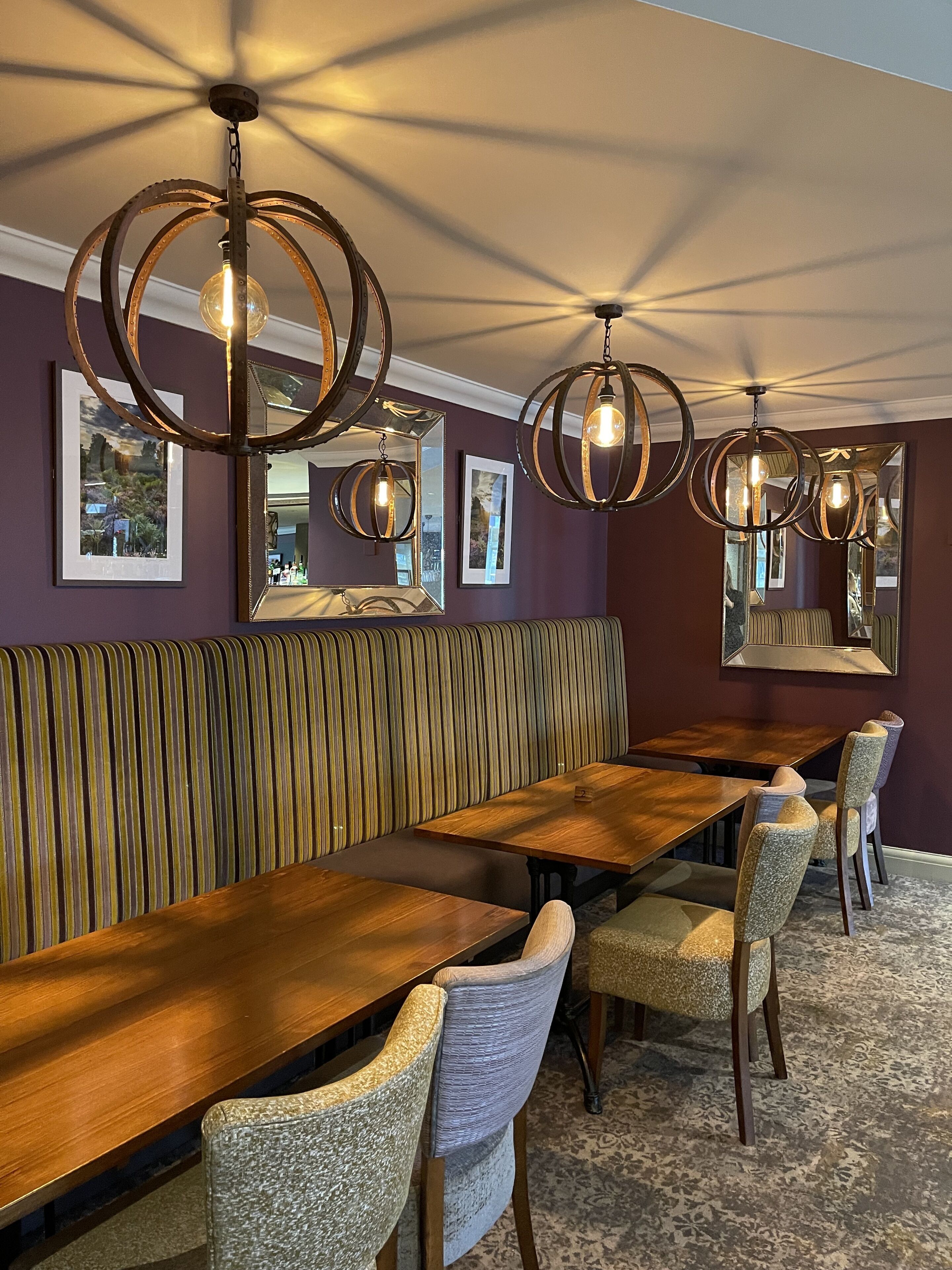 A dining area with a long wooden table, cushioned benches, and upholstered chairs.
