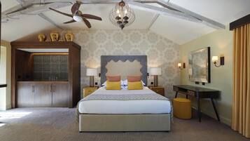 A spacious bedroom with a large bed, a wooden wardrobe, a desk with a chair, and a ceiling fan.
