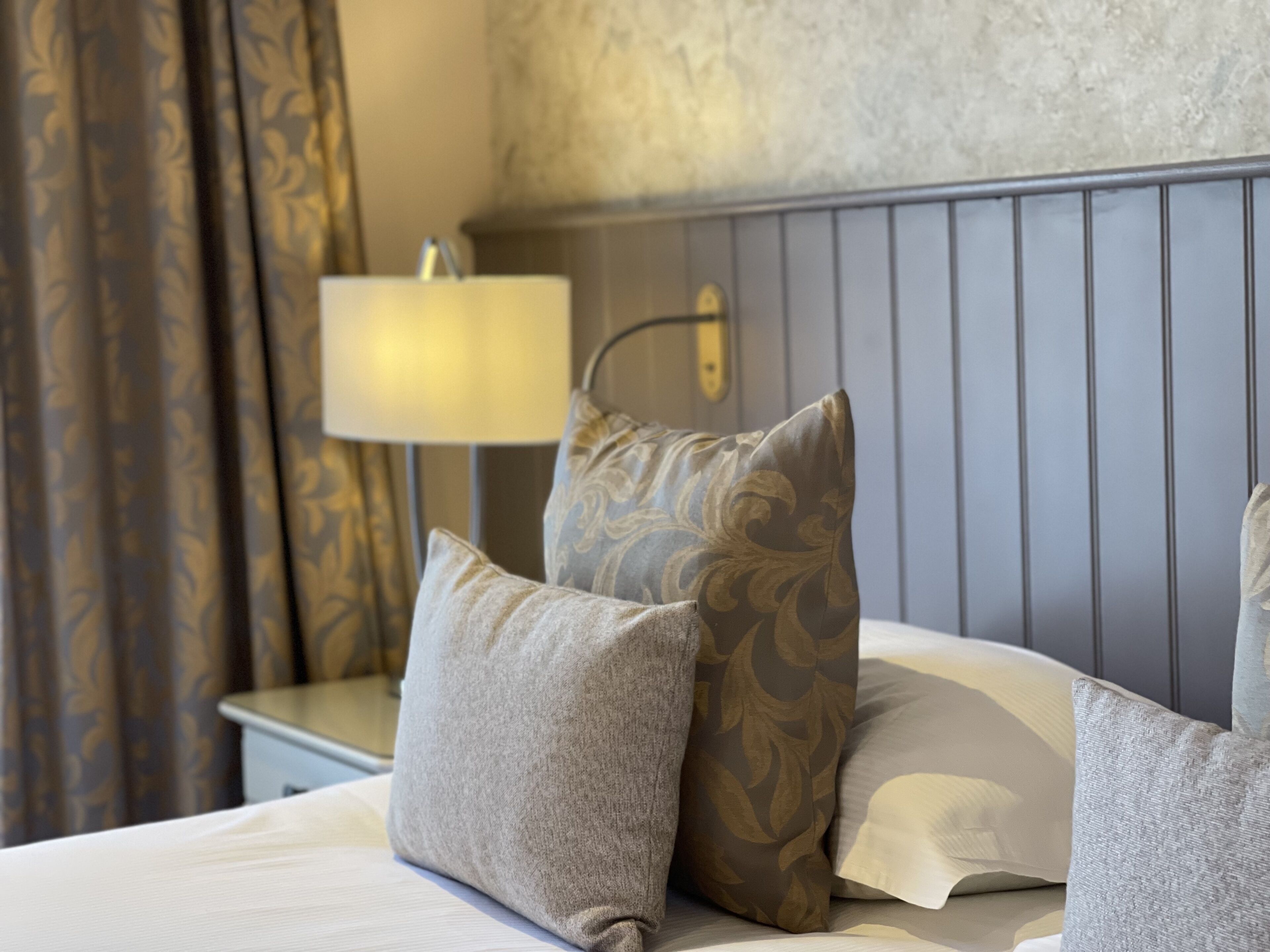A neatly made bed with pillows and a bedside lamp.