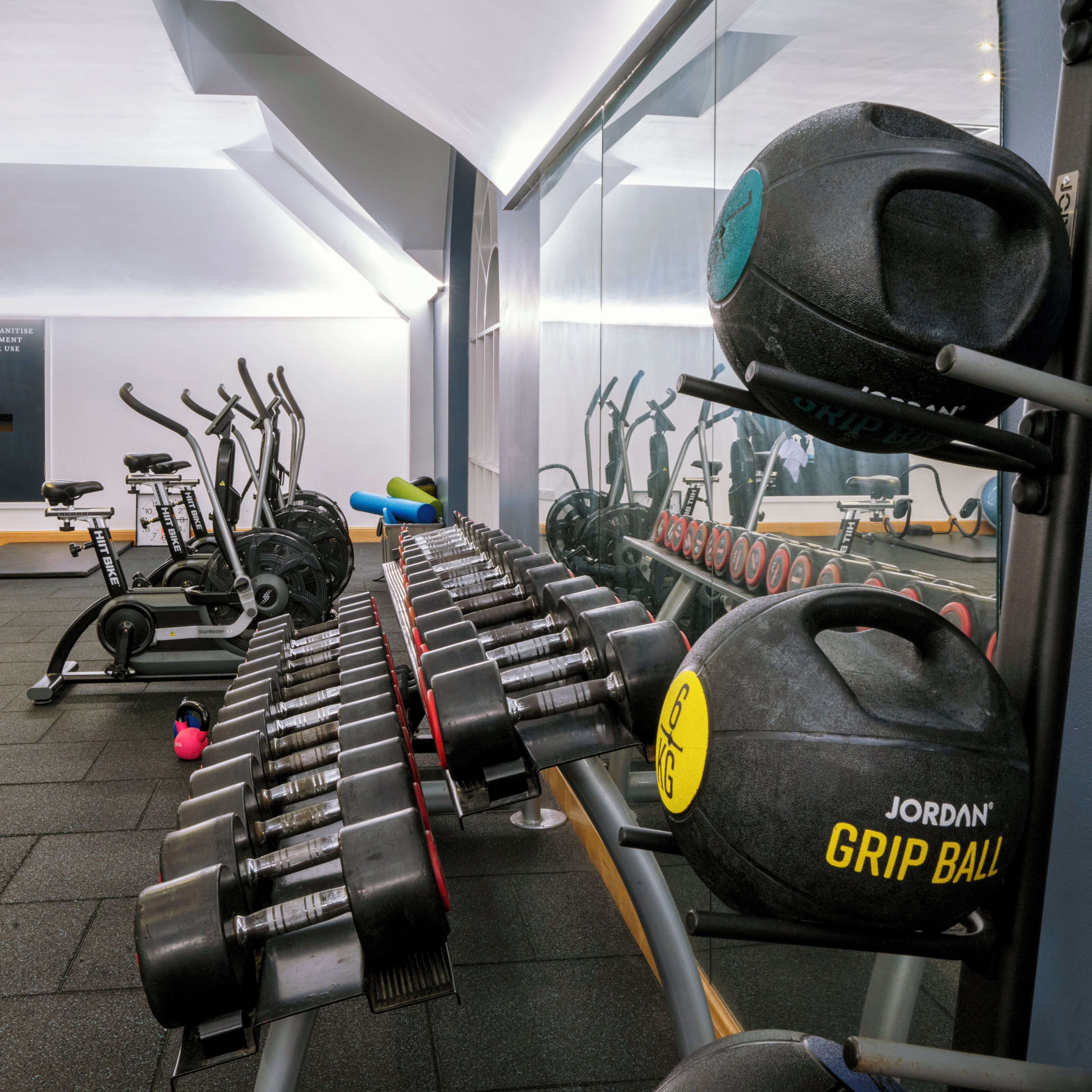 A gym with various exercise equipment, including dumbbells, a kettlebell, and exercise bikes.