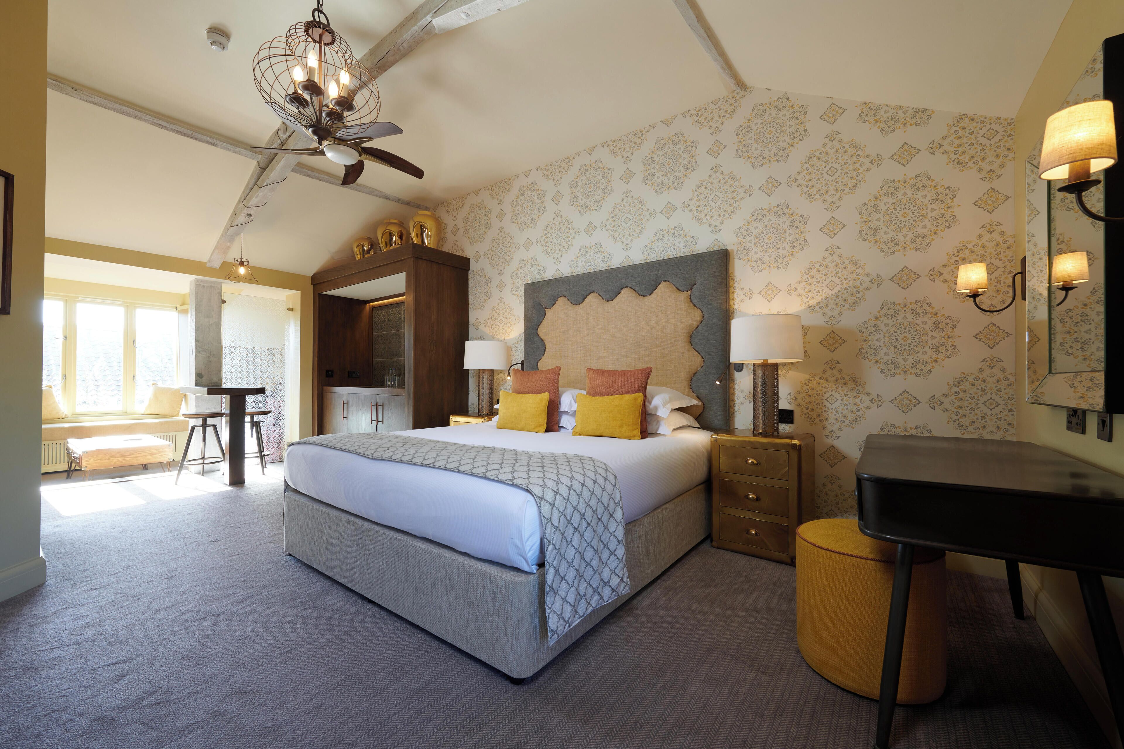 A spacious bedroom with a large bed, bedside tables, a desk, and a chair.